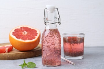 Glass bottle of drink with chia seeds and grapefruit on grey table