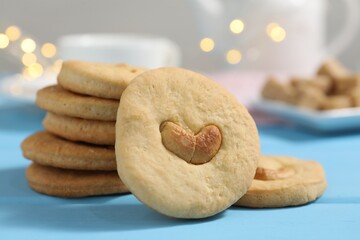Tasty cashew cookies on light blue wooden table, closeup