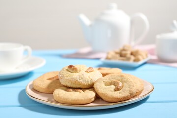 Plate with tasty cashew cookies on light blue wooden table, closeup