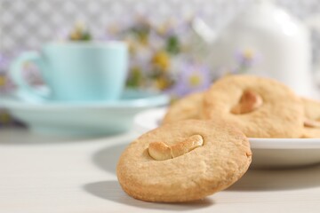 Plate with tasty cashew cookies on white wooden table, closeup. Space for text