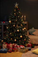 Vertical background image of decorated Christmas tree and presents in dim cozy home interior with and gold details copy space