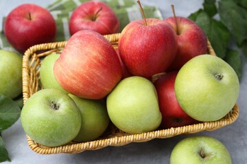 Fresh ripe apples in wicker basket on grey table, closeup