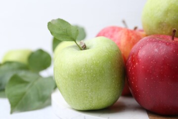 Fresh ripe apples and green leaves on table, closeup