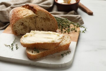 Fresh bread with butter and thyme on white table, closeup