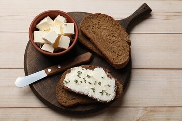 Fresh bread with butter, thyme and knife on light wooden table, top view