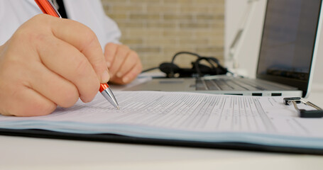 Close up shot checklists of recent patients done by doctor on laptop and also on paper. Healthcare...