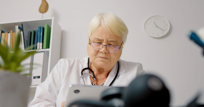 Close up female doctor using tablet to process patients data for medical analysis. Medical worker receiving laboratory result through email.