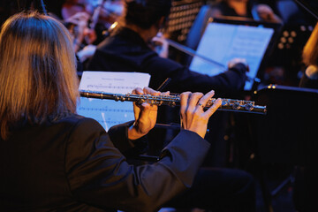 A woman is skillfully playing a beautiful flute as part of a vibrant orchestra during a thrilling...