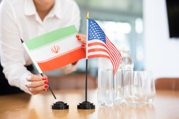 Closeup of national flags of Iran and United States in hands of female office secretary preparing...