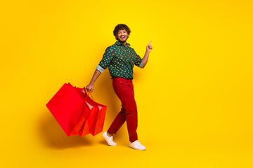 Full body portrait of nice elegant young man shop bags direct finger empty space wear shirt isolated on yellow color background