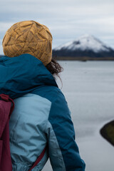 Woman in winter clothing admiring snow-capped mountain by lake