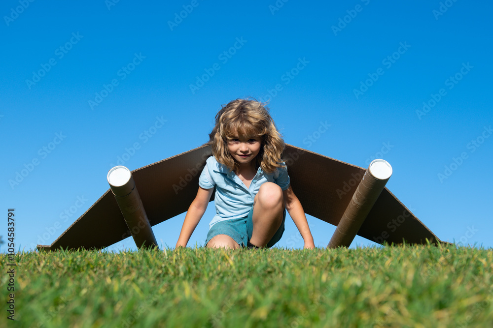 Wall mural child boy playing with cardboard toy airplane wings craft in sky with copy space for text. creative 