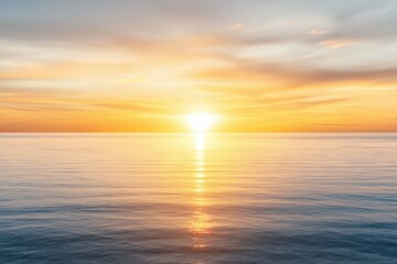Fototapeta premium A serene sunset over a calm sea, featuring vibrant orange and yellow hues reflecting on tranquil water.