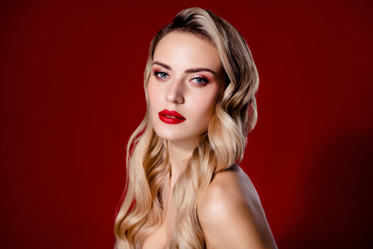 Portrait of lady with bright make up look with blonde curls isolated red color background