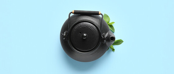 Tea pot and mint on light blue background, top view