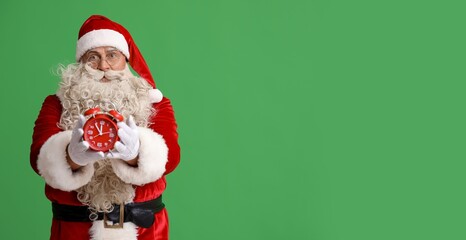 Santa Claus with alarm clock on green background with space for text