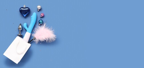 Sex toys, shopping bag and Christmas decorations on blue background with space for text, top view