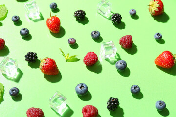 Composition with ice cubes and fresh berries for lemonade on green background