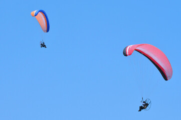 Two paragliders are paragliding against clear blue sky