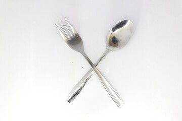 A simple, minimalist photo of a fork and spoon crossed against a white background.