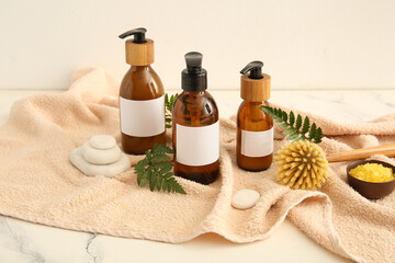 Bottles of shampoo, brush, sea salt and spa stones on white background
