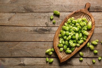 Board with fresh green hops on wooden background