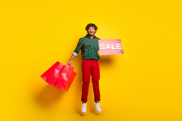 Full body portrait of nice elegant young man jump sale blank shop bags wear shirt isolated on yellow color background