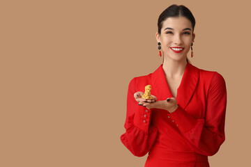 Beautiful young happy woman with golden dragon figurine on brown background. Chinese New Year...