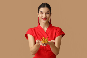 Beautiful young happy woman with golden dragon figurine on brown background. Chinese New Year celebration