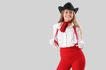 Stylish young woman with suspenders on white background