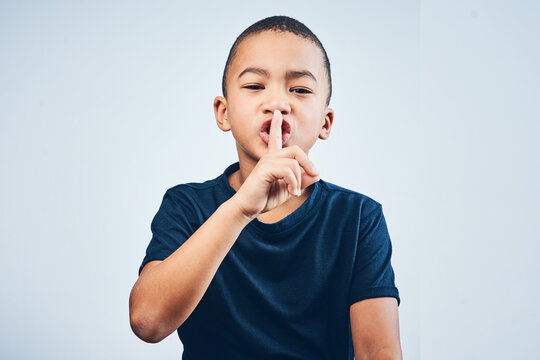 Boy, portrait and finger to shush in studio, privacy and mystery news on white background. Male person, child and secret announcement or gossip revelation, emoji and quiet gesture for confidential