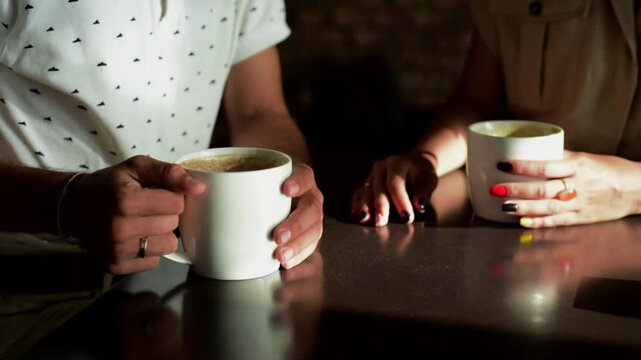 Man and woman drinking coffee. framing on hands. Close up woman and man holding cups of coffee on table