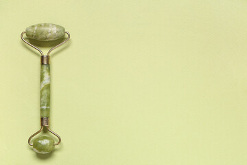 Jade face massage roller on green background