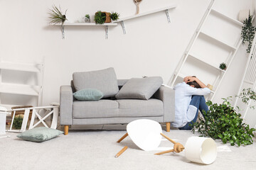 Young woman sitting near sofa during earthquake at home