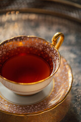 fancy pink and gold pattern teacup and saucer on silver tray with black tea