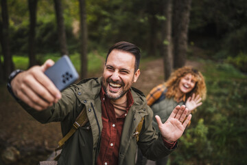 Fototapeta premium Adult man hiker take a self portrait while his wife stand behind him