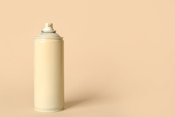 Spray paint can on beige background