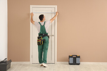 Male worker measuring door at home