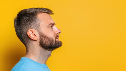 Fototapeta premium Young man in a stylish shirt poses confidently against a bright yellow background, perfect for a fresh look.