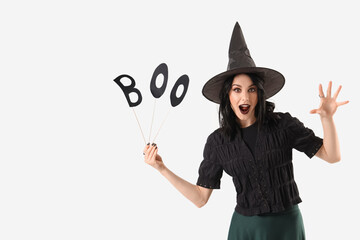 Beautiful young scary woman dressed as witch for Halloween with word BOO isolated on white...