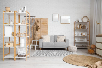 Interior of light living room with grey sofa, pampas grass and shelving units