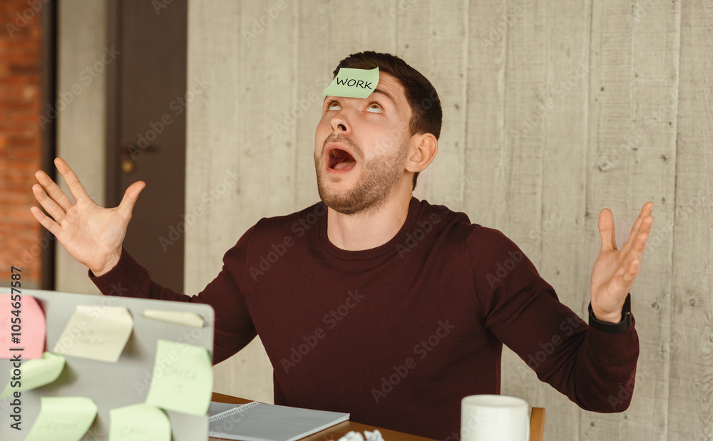 Poster exhausted office worker guy having sticky notes on face and everywhere sitting at workplace indoor. 