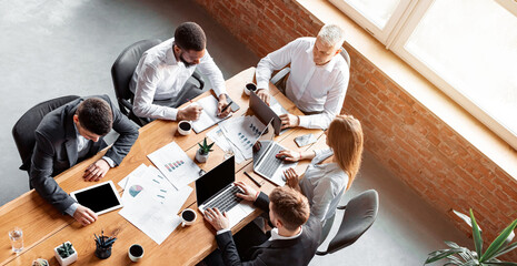 Corporate Lifestyle. Colleagues Working Together On Business Project Sitting At One Table In Modern Office. Above View
