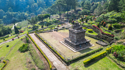 The Gedong Songo Temple complex rests on a hillside, surrounded by misty green mountains. The ancient stone temples are scattered across the landscape, offering breathtaking views and a serene, 