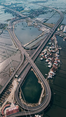 A toll road curves through a vast expanse of floating fish farms, with kerambas scattered across the calm water beneath the highway.