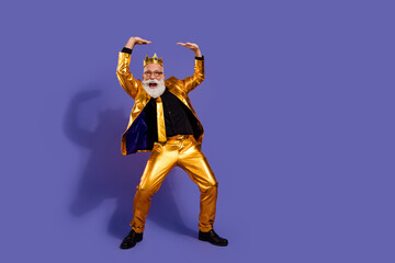 Full size photo of charismatic extravagant man hold above empty space golden costume isolated on violet color background