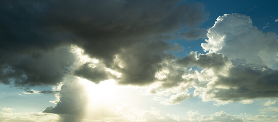Beautiful sunset sky with clouds. Sky blue and orange light of the sun through the clouds in sky. Background of dark clouds before storm. Dramatic clouds. Apocalyptic sky, dark cloud.