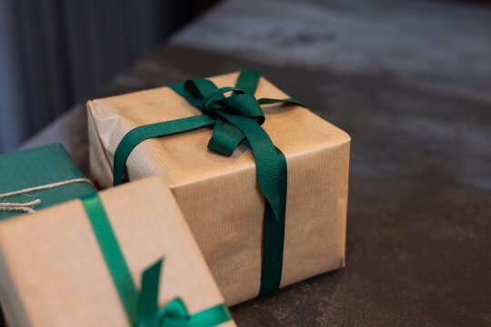 Gift boxes wrapped with green ribbons on table, ready for Christmas celebration, at home