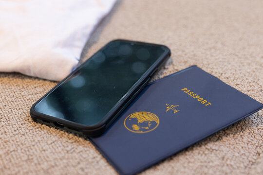 Smartphone resting on passport on carpet, ready for travel adventure, copy space, at home
