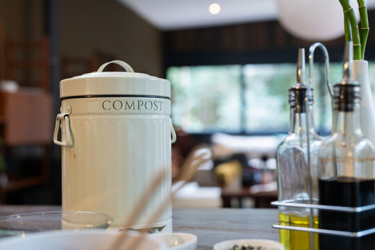 Compost bin on kitchen counter with olive oil bottles in modern home